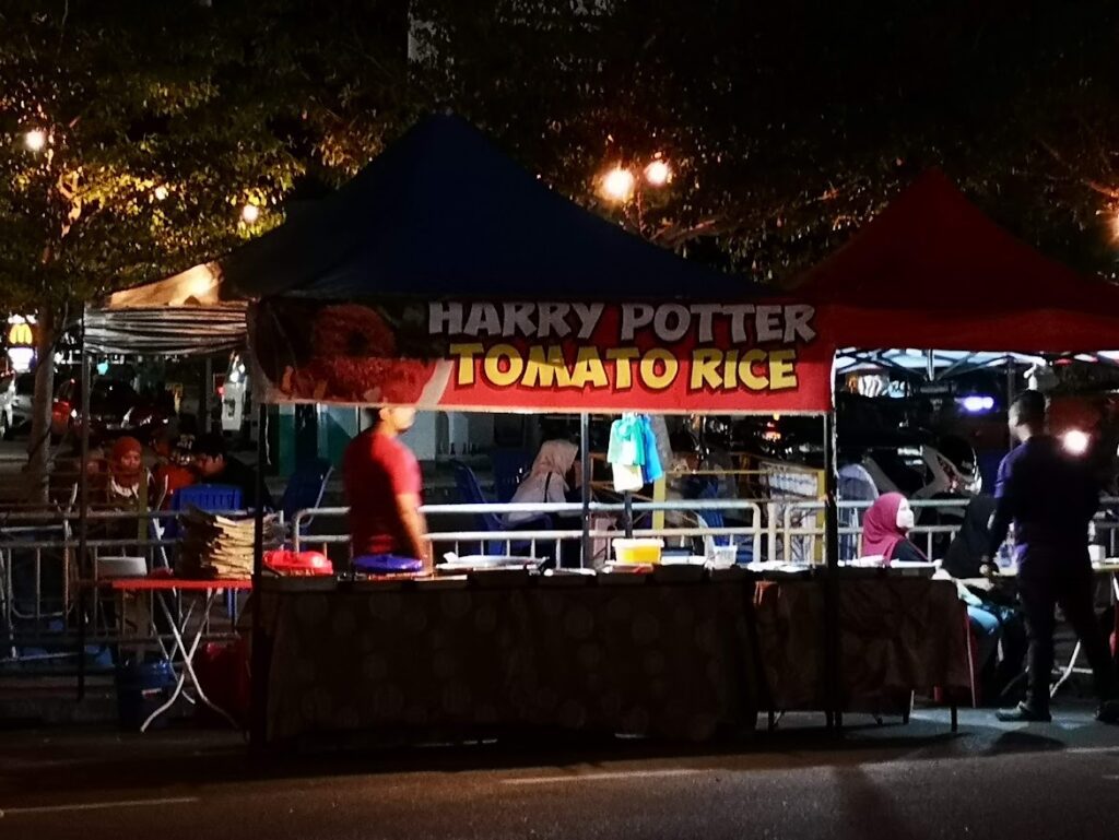 a stall at the side of the road selling food with a sign above that says "Harry Potter Tomato Rice"