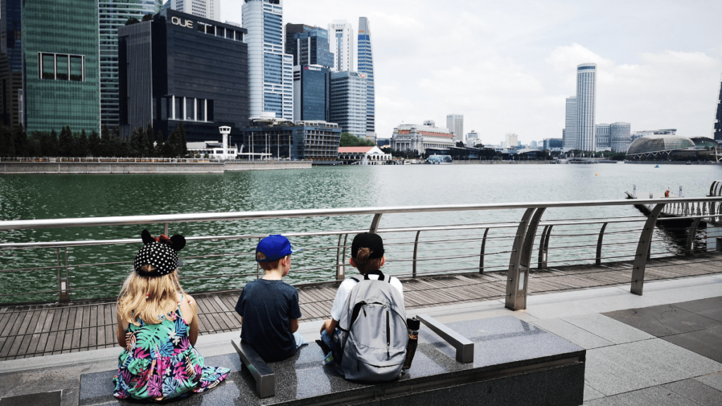 My 3 kids sat on a bench looking into the harbour at Singapore