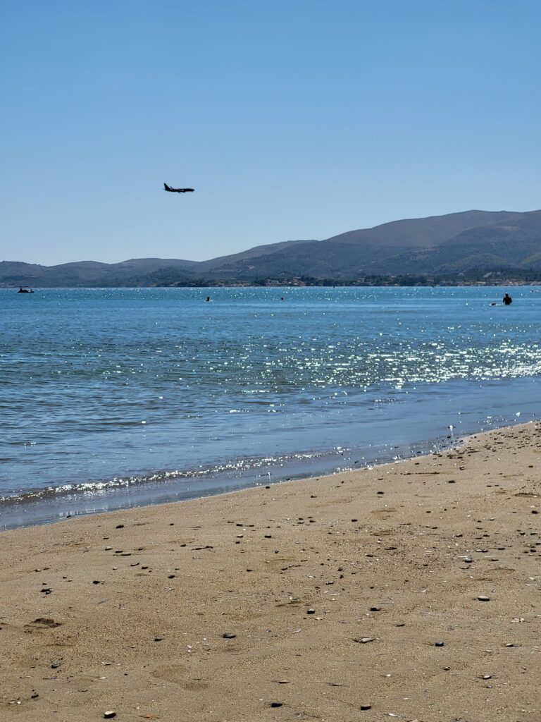 A plane coming in for landing over the blue sea at Kalamaki beach